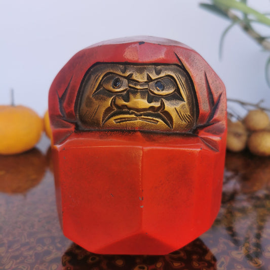 Daruma en métal rouge et doré, poupée japonaise de caractère traditionnel.