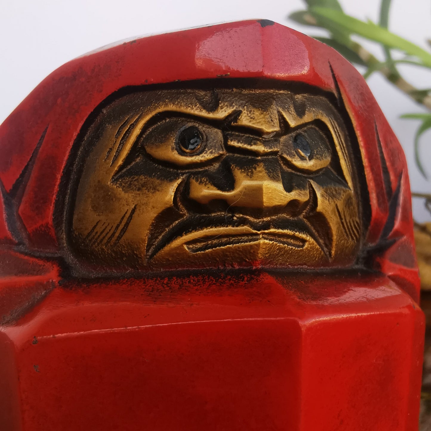 Daruma en métal rouge et doré, poupée japonaise de caractère traditionnel.