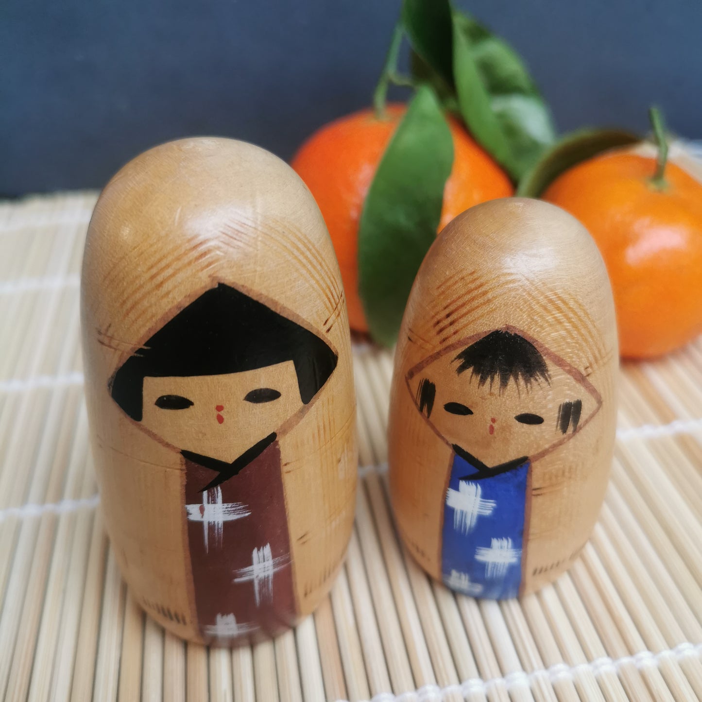 Joli duo de mini Kokeshi, représentant un frère et une sœur ou un parent et son enfant, vêtus de vêtements d'hiver