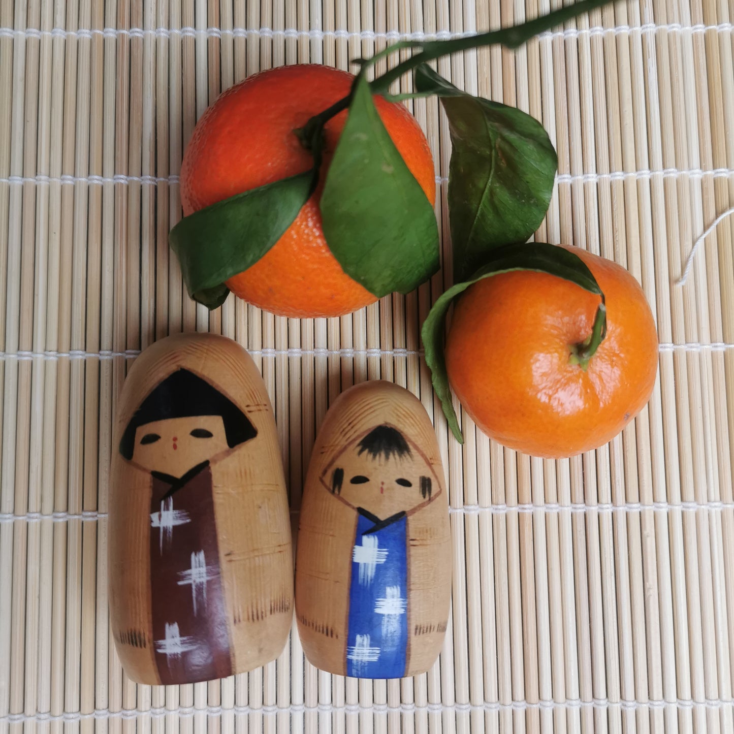 Joli duo de mini Kokeshi, représentant un frère et une sœur ou un parent et son enfant, vêtus de vêtements d'hiver