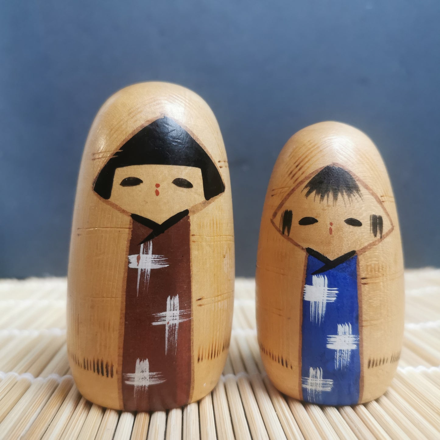 Joli duo de mini Kokeshi, représentant un frère et une sœur ou un parent et son enfant, vêtus de vêtements d'hiver