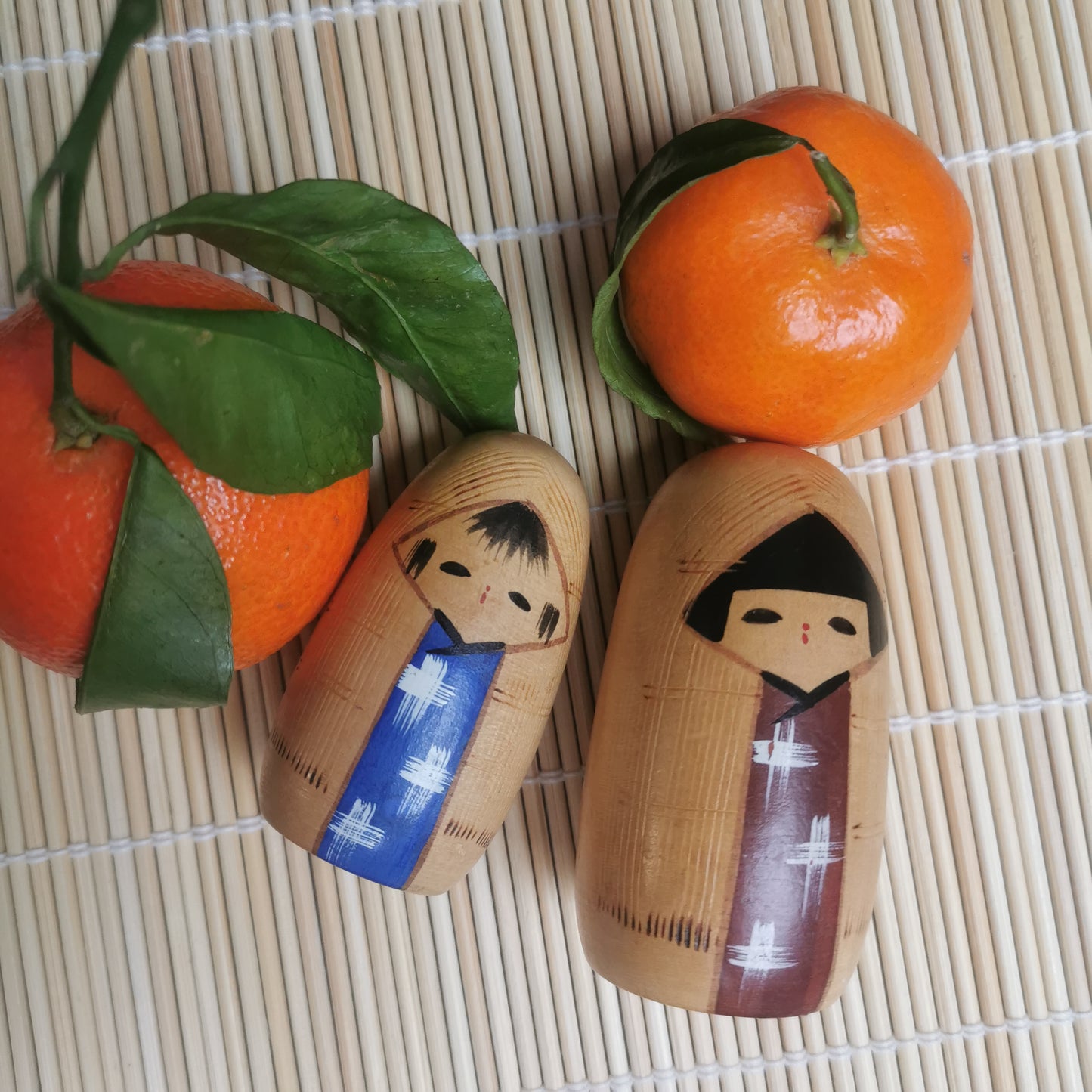 Joli duo de mini Kokeshi, représentant un frère et une sœur ou un parent et son enfant, vêtus de vêtements d'hiver